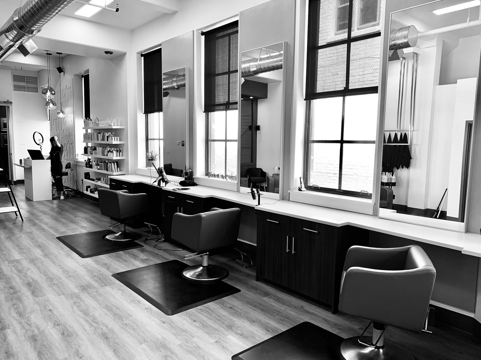 Row of barber chairs facing wall mirrors in a black-and-white salon interior