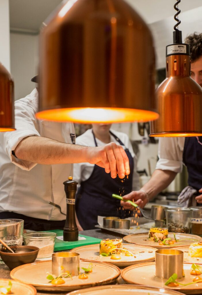 Chef plating dishes under copper heat lamps