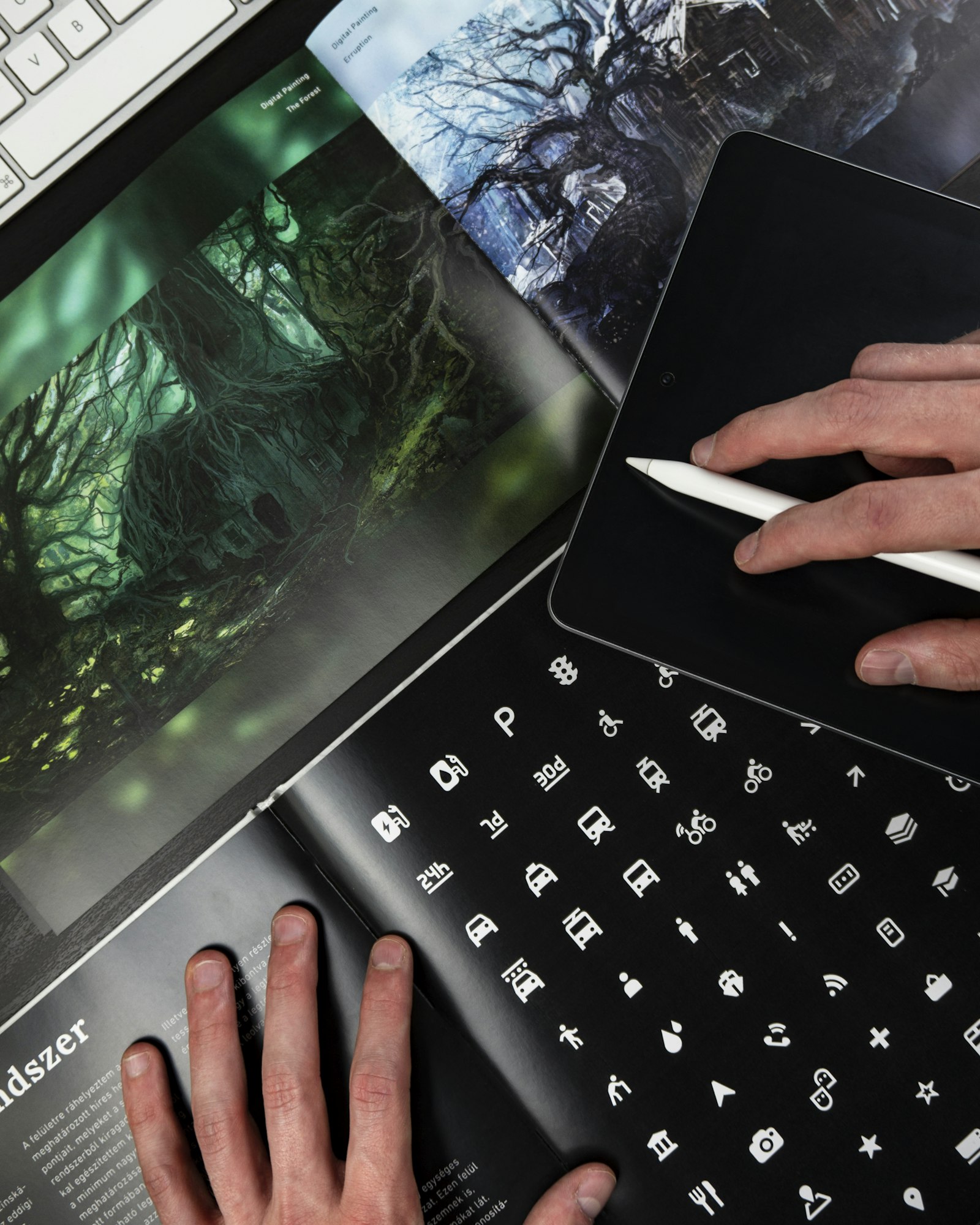 Hands using a stylus on tablet over design prints