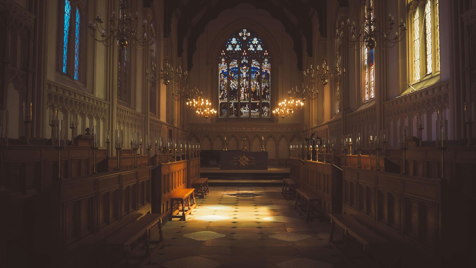 Warm light pooling in a Gothic church with stained glass and carved choir stalls