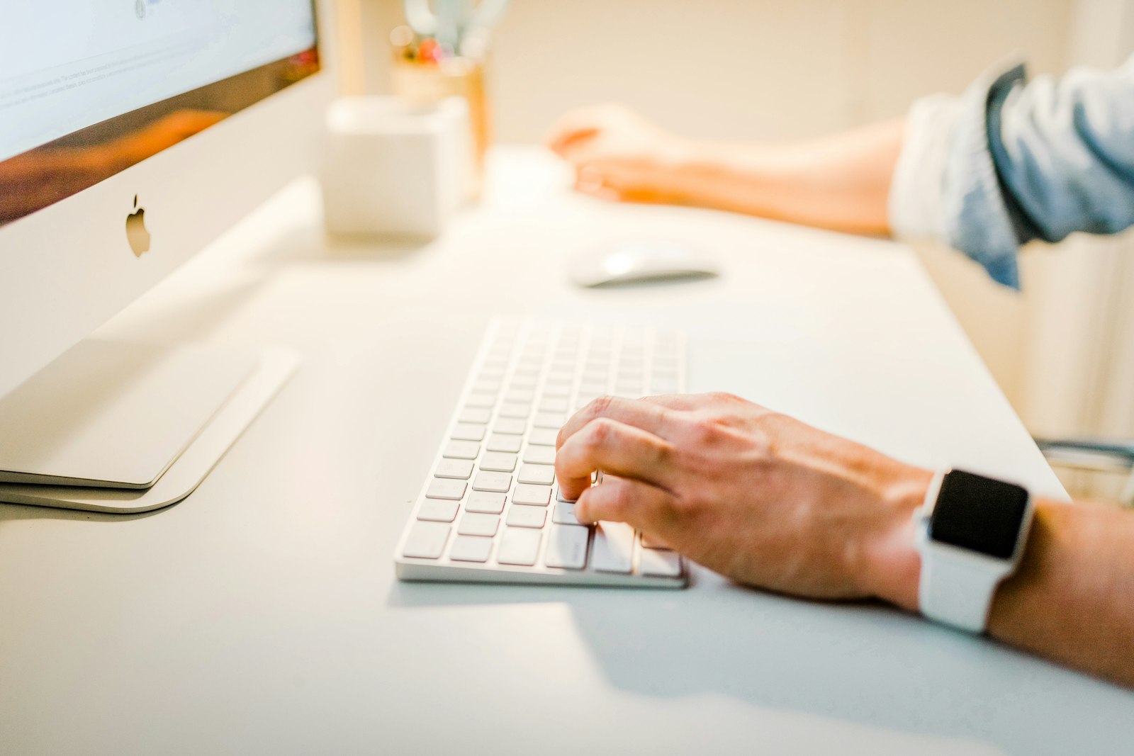 Hands typing on a keyboard at a bright white desk