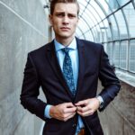 Young man buttoning a navy suit