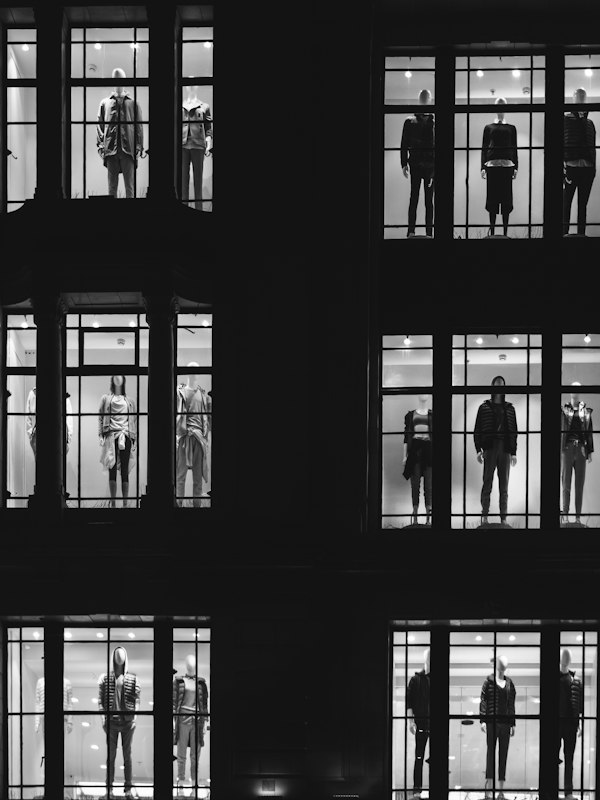 Lit store windows with mannequins in a dark facade