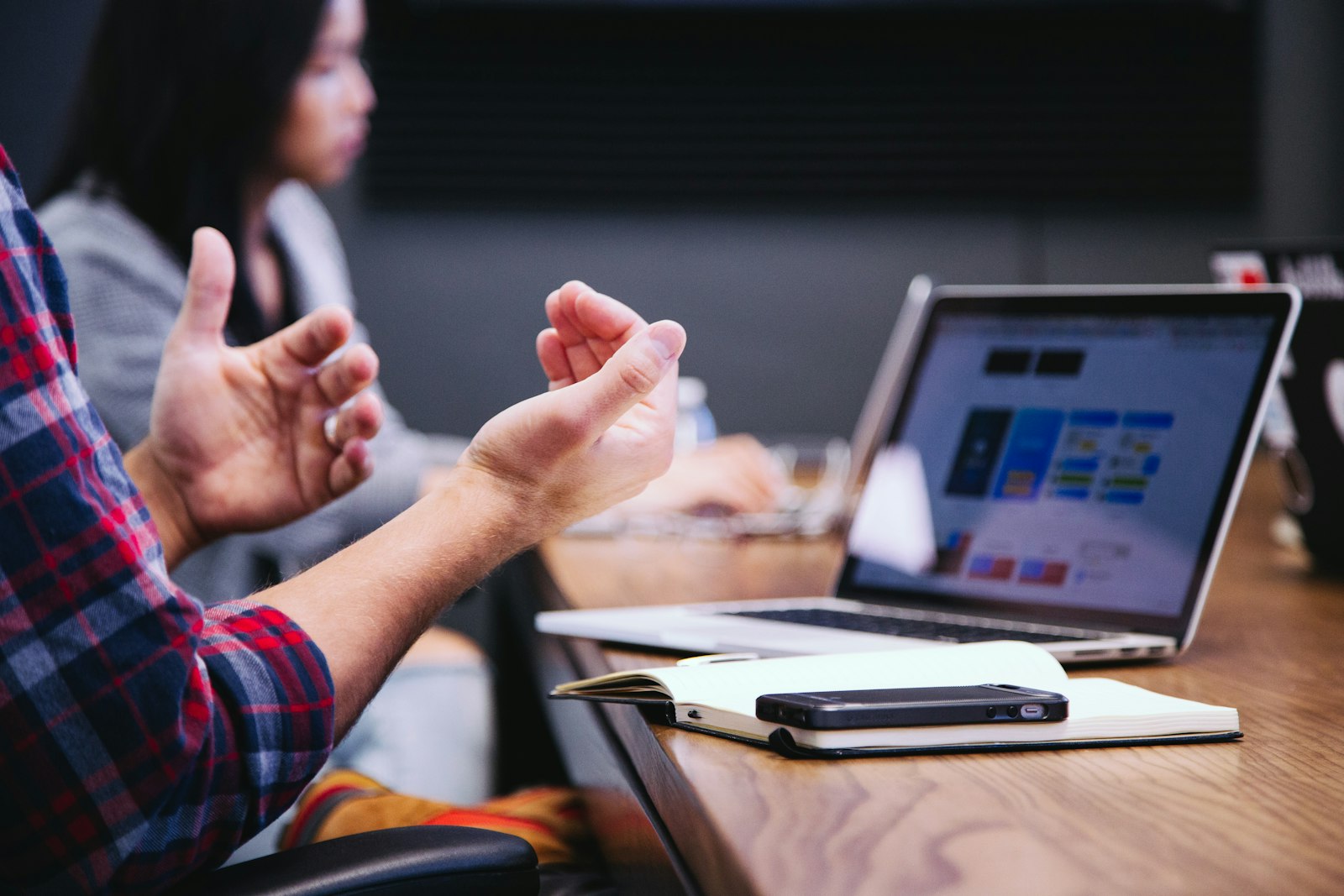 Hands gesturing over a laptop at a meeting table