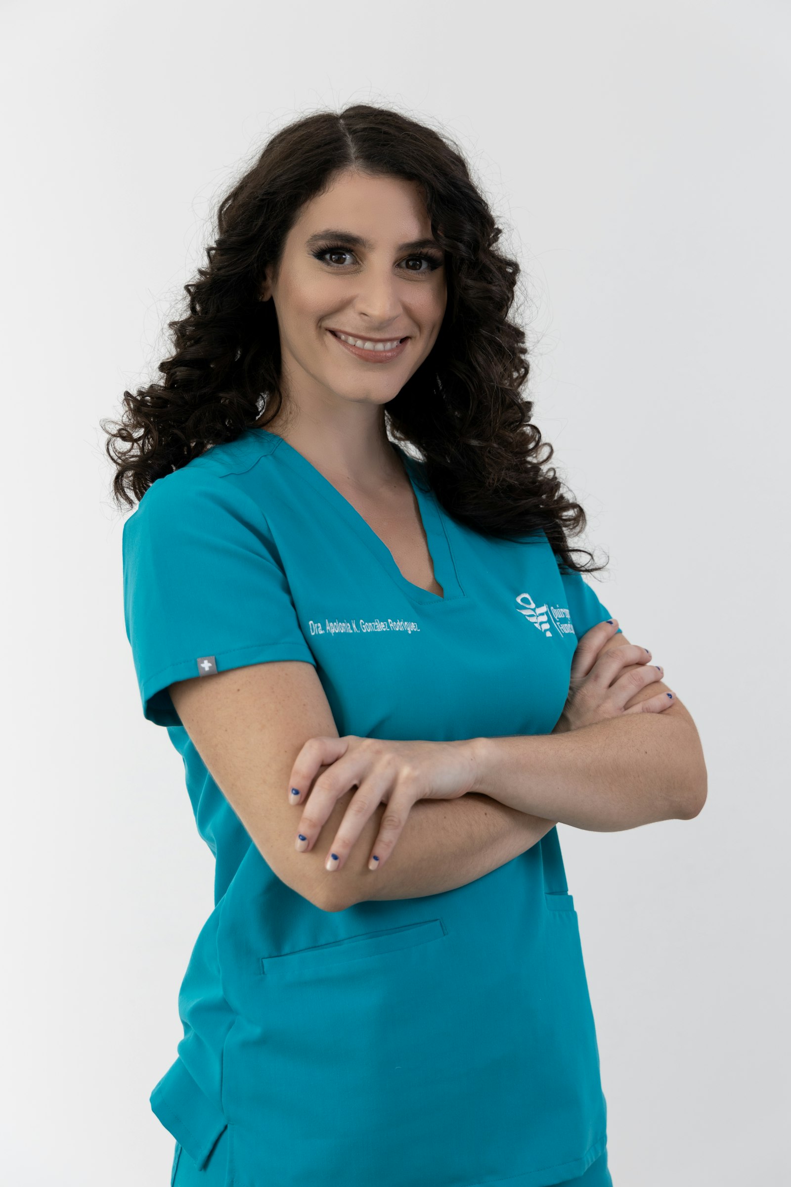 Smiling woman in teal scrubs with arms crossed