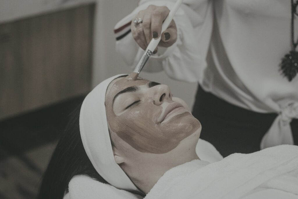 Clay face mask being brushed onto a woman at a spa